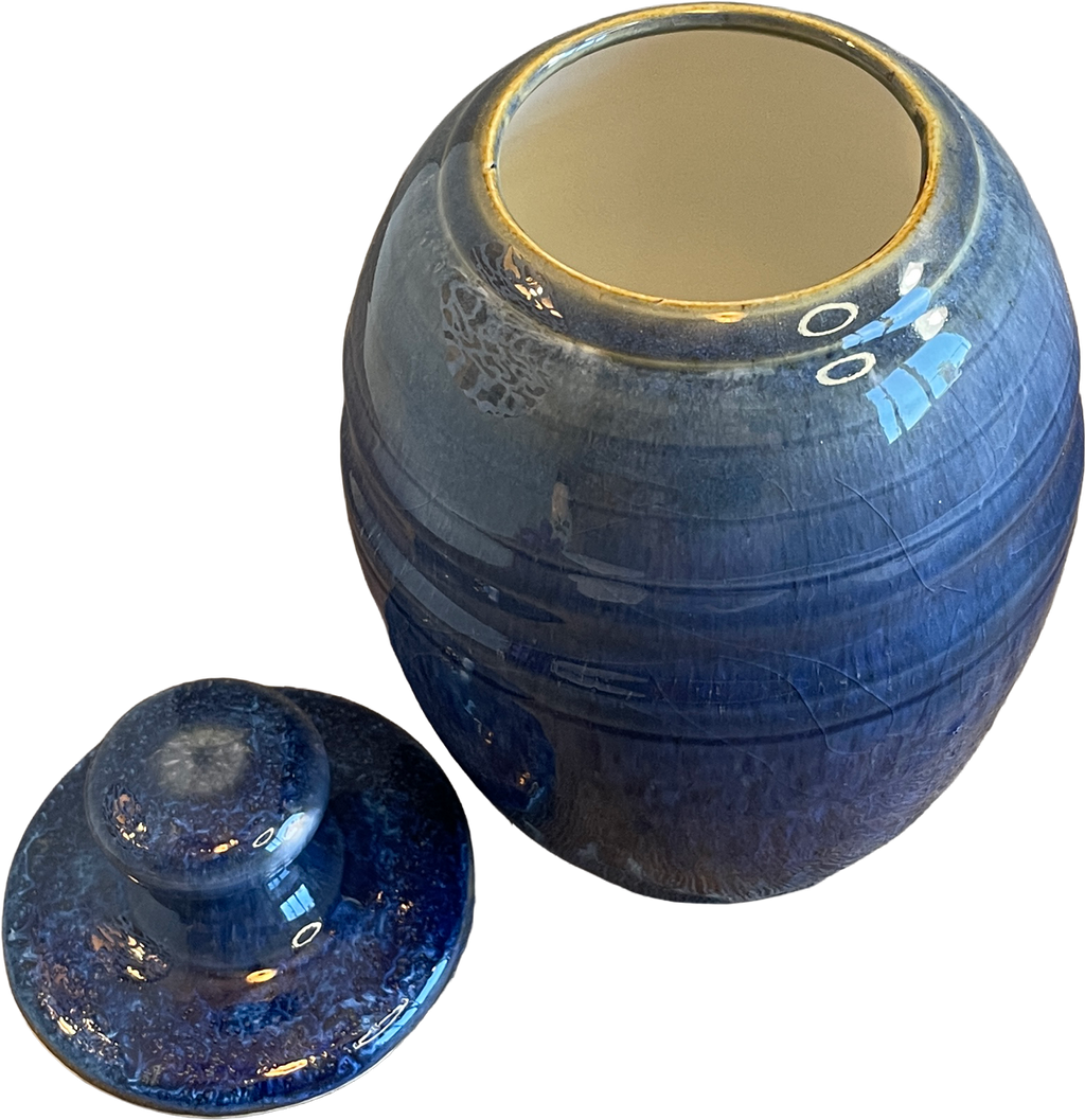 A blue glazed ceramic jar with its matching lid placed in front, set against a plain white background.
