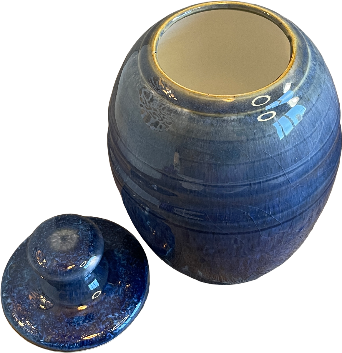 A blue glazed ceramic jar with its matching lid placed in front, set against a plain white background.