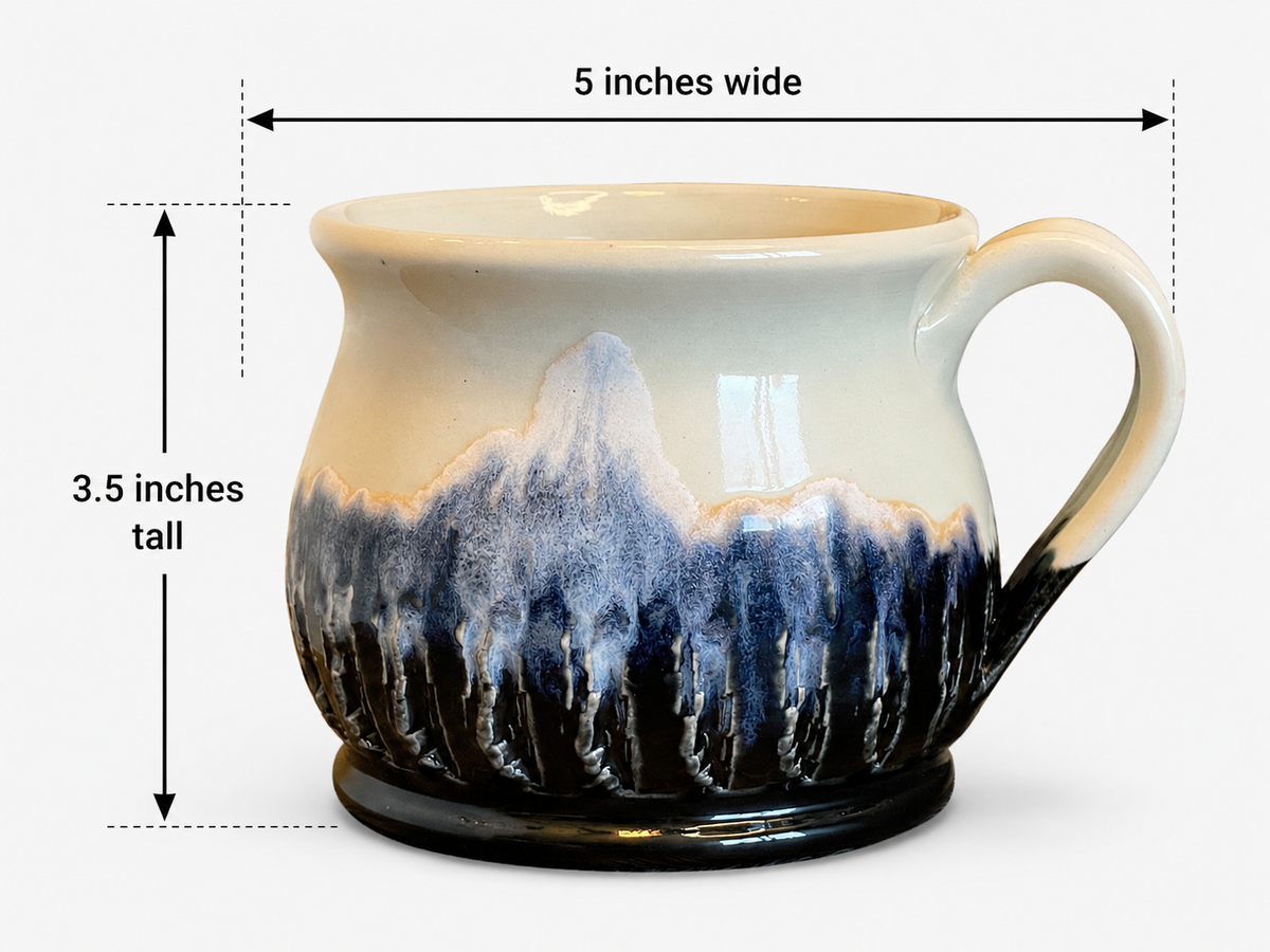 A ceramic mug with a cream and blue mountain landscape glaze design, shown with dimension lines indicating it is 5 inches wide and 3.5 inches tall, on a light gray background.